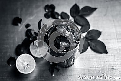 Popular Indian/Asian sharbat i.e GULAB KA SHARBAT with sliced lemon,Citrus Ã— limon,Rosa,rose petals and mint leaves on a silver Stock Photo
